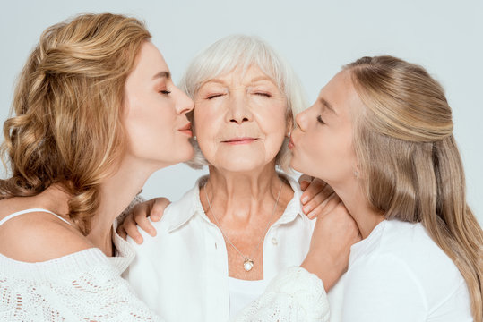 Granddaughter And Mother Kissing Grandmother With Closed Eyes Isolated On Grey