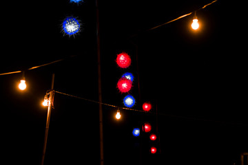 Orange, blue and red lanterns hanging on the wires  And turn on the light during the night.