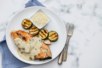 salmon with sauce and grilled vegetables on white plate
