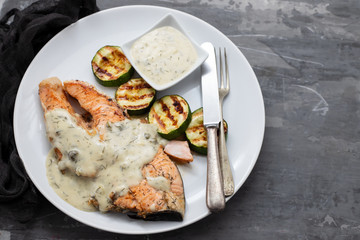 salmon with sauce and grilled vegetables on white plate