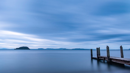Obraz premium Long exposure of a wooden pier with dramatic sky on Lake Taupo New Zealand