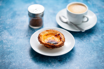 typical portuguese egg tart pastel de nata with cup of coffee on ceramic background