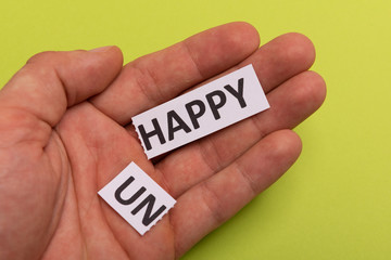 man hand holding card with text unhappy, cutting word 'un' so it written 'happy'. Copy space. Lime background. Studio shoot