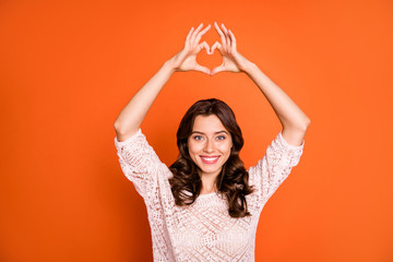 Naklejka premium Portrait of lovely charming girl date with her boyfriend make heart figure finger show passionate love sign wear good looking clothing isolated over orange color background