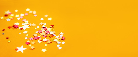 Yellow holiday background with colorful star confetti. Good background for Christmas and New Year...