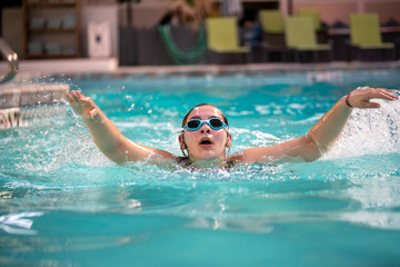 Teen Girl swimming in an indoor pool. Teen healthy lifestyle concept. 