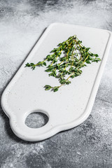Sprigs of thyme on a white cutting Board. Gray background. Top view. Space for text