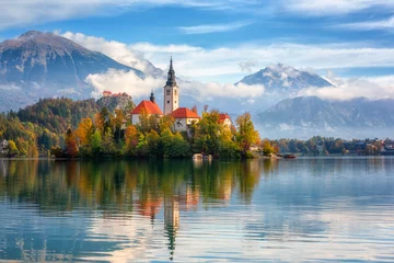 Berühmter alpiner Bleder See (Blejsko jezero) in Slowenien, erstaunliche Herbstlandschaft. Szenische Ansicht des Sees, der Insel mit Kirche, der Burg von Bled, der Berge und des blauen Himmels mit Wolken, Reisehintergrund im Freien © larauhryn