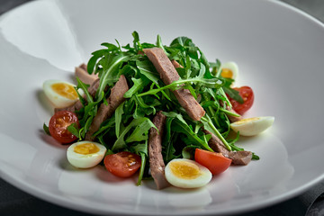 Tasty italian salad of beef tongue with eggs, arugula, tomato, spices and sauce