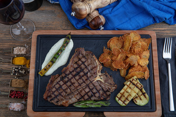 Barbecued t-bone steak seasoned with fresh herbs and marinade served with a cutting board in a...