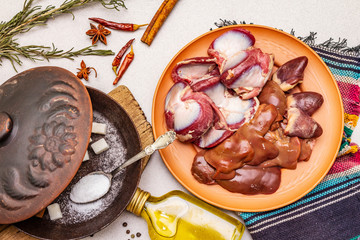 Fresh raw duck offal: heart, liver, stomach. Dry spices, salt, sugar, oil. Frying pan, stone concrete background
