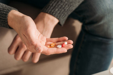 cropped view of sick man with handfull of pills