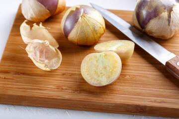 Ripe tomatillo (Mexican husk tomato, Physalis philadelphica, Vegetable physalis) on cutting board.
