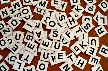 A pile of black letters tiles on brown card bord