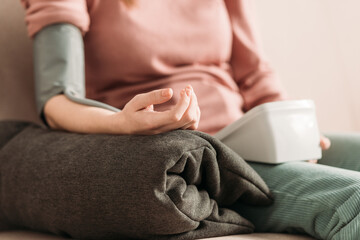 Fototapeta premium cropped view of girl measuring blood pressure while holding hand on pillow