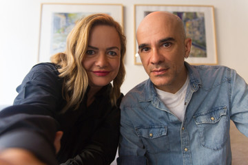 Joyful worried middle aged couple taking selfie at home. Caucasian man and woman in casual looking...