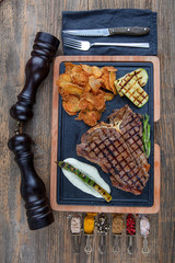 Barbecued t-bone steak seasoned with fresh herbs and marinade served with a cutting board in a...