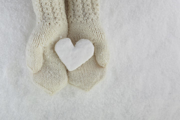 Snow Heart in Hands with Mittens on white snow background