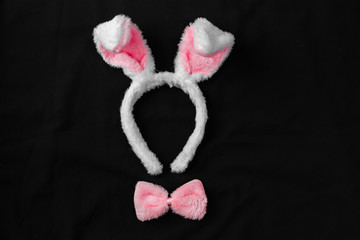 Top view of cute bunny ears with a small pink bow on wooden background.