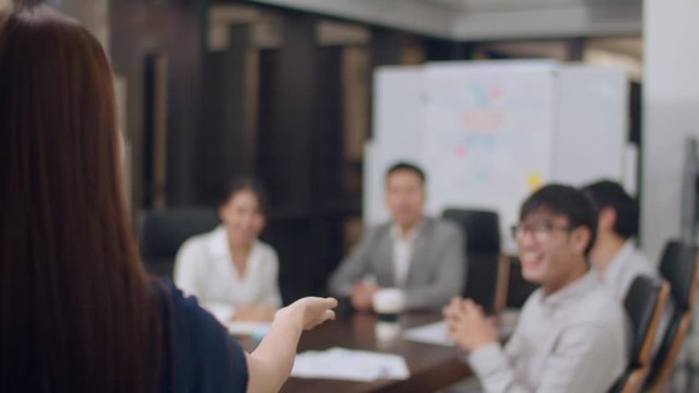 Asia businessmen and businesswomen meeting brainstorming ideas conducting business presentation project colleagues working together plan success strategy enjoy teamwork in small modern night office.