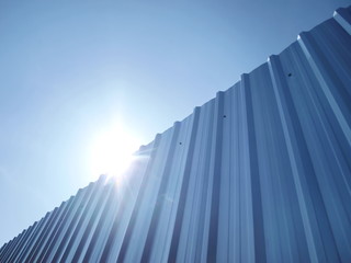 Fototapeta na wymiar Horizontal silvery galvanized walls and bright blue skies Along with the sun light on the blue sky background With copy space