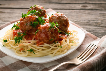 Close up plate of spaghetti with meatballs in tomato sauce sprinkled with parsley on table-napkin...