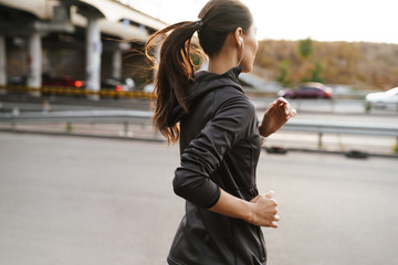 Strong fitness woman running outdoors by street.