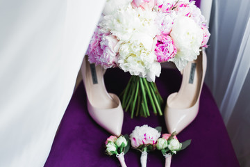 Pair of elegant and stylish bridal shoes with a bouquet with roses and other flowers