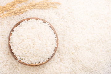 Raw white polished milled edible rice crop on white background in brown bowl, organic agriculture design concept. Staple food of Asia, close up.