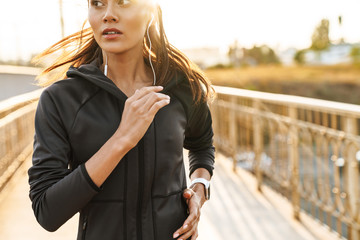 Strong fitness woman running outdoors by street.