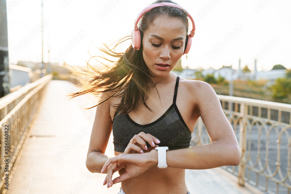 Wall mural Sports concentrated woman looking at watch clock