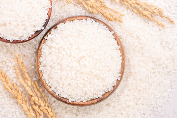 Raw white polished milled edible rice crop on white background in brown bowl, organic agriculture design concept. Staple food of Asia, close up.
