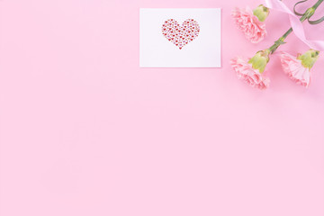 Beautiful, fresh elegant carnation flower bouquet with white greeting thanks gift card isolated on bright pink color background, top view, flat lay concept.