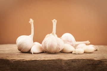 Garlic on old wooden table with brown background. vintage filter