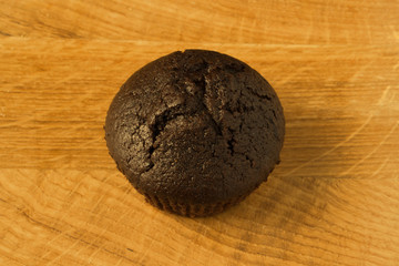 Obraz na płótnie Canvas Appetizing chocolate muffin (cupcake) on a wooden plate
