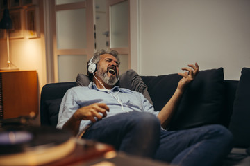 middle aged man relaxing at his home listening records - obrazy, fototapety, plakaty