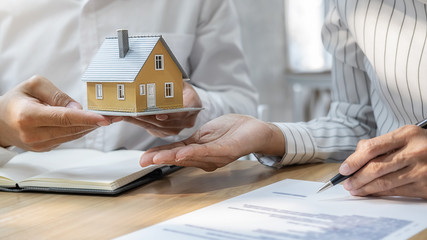House model with agent and customer discussing for contract to buy, get insurance or loan real...