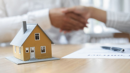 House model with agent and customer discussing for contract to buy, get insurance or loan real estate or property.