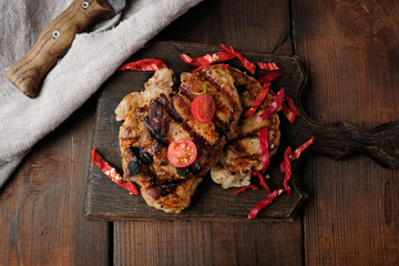 grilled pork pieces of meat on a grill lie on a vintage wooden board