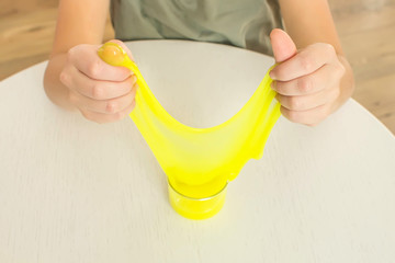 Modern toy called slime. Child playing transparent yellow slime. Hands holding a mucus on a white background. Selective focus.
