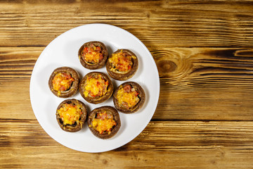 Baked mushrooms stuffed with minced meat, mushroom, paprika, onion and cheese on wooden table. Top view