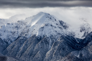 Beautiful mountain panorama in winter with fog and clouds. Bucegi mountains seen from Postavaru, Romania.