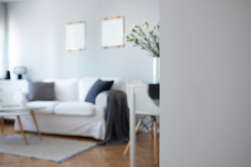 Fototapeta na wymiar Copy space on empty white wall blurred photo of beautiful studio apartment with small living room