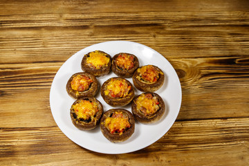 Baked mushrooms stuffed with minced meat, mushroom, paprika, onion and cheese on wooden table