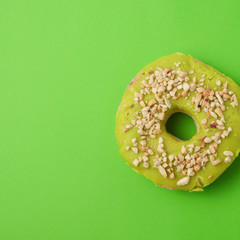 round baked donut with green pistachio glaze sprinkled with crushed nuts