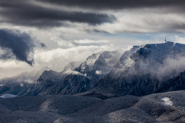 Beautiful mountain panorama in winter with fog and clouds. Bucegi mountains seen from Postavaru, Romania.