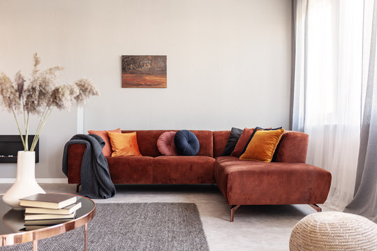 Real Photo Of Warm Color Cushions On A Red Couch Standing Next To The Window In Cozy Living Room Interior