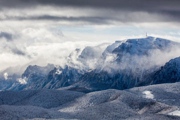 Beautiful mountain panorama in winter with fog and clouds. Bucegi mountains seen from Postavaru,...