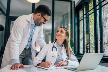 Doctor talking to his young intern in the office. Internship, education and medicine concept.