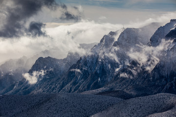 Beautiful mountain panorama in winter with fog and clouds. Bucegi mountains seen from Postavaru, Romania.